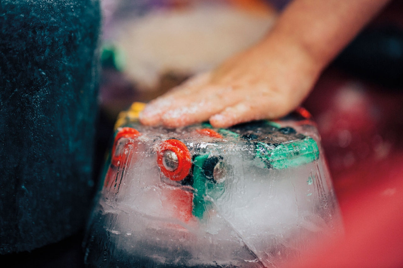 An icy toddler hand pressed against a block of ice with toys frozen inside. Photo: Kyle Sparks