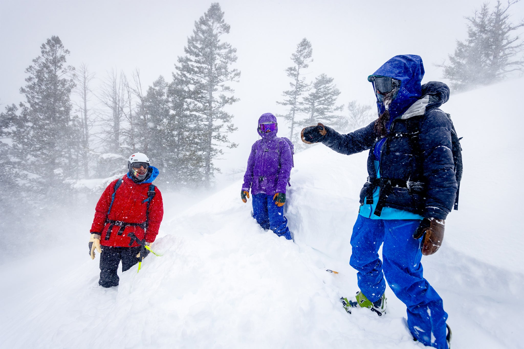 Billimoria (left) and Zynobia (center) try to listen over howling wind as Dhamsania (right) points out the best route down the mountain. Teton Range, Wyoming.