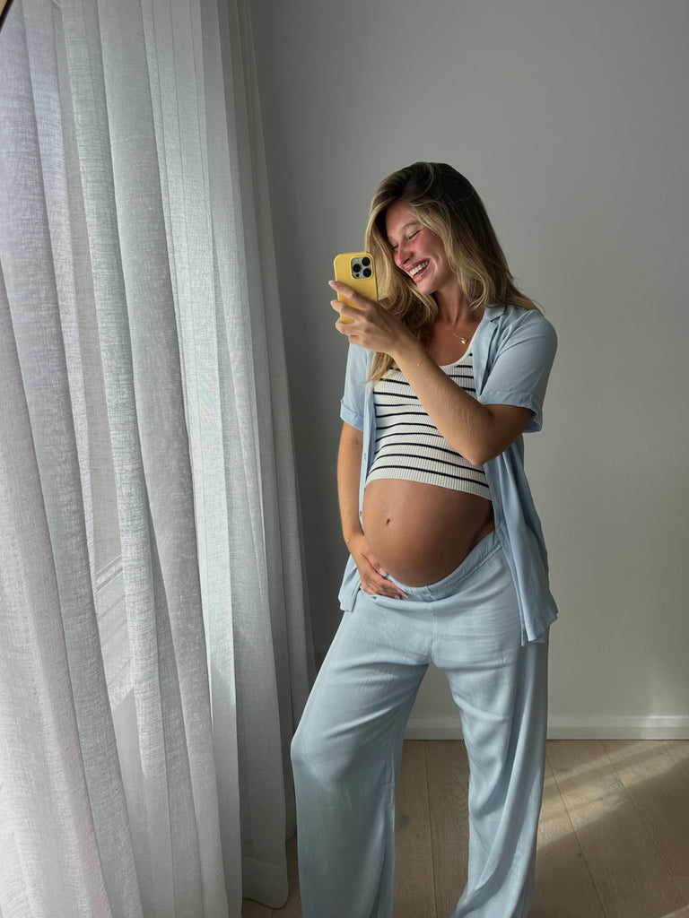 Pregnant woman wearing striped maternity crop under maternity matching set in blue