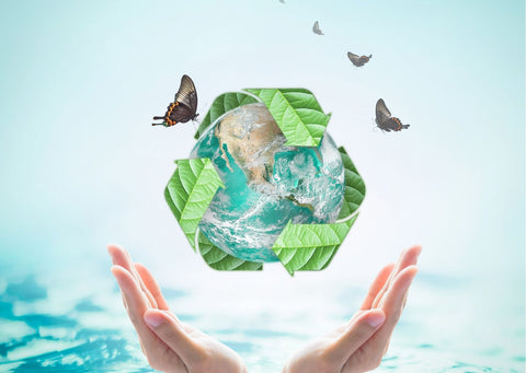 a womans hands are around a recycled symbol around a globe with butterflies flying around it