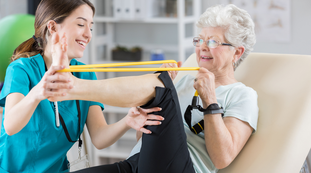 A physical therapist guiding an elderly woman through exercise routines using a physical therapy band for improved fitness and well-being.