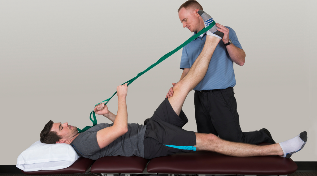 A physical therapist providing treatment to a man using physical therapy bands.