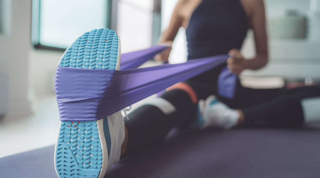 Stretching exercise with purple resistance band for foot flexibility.