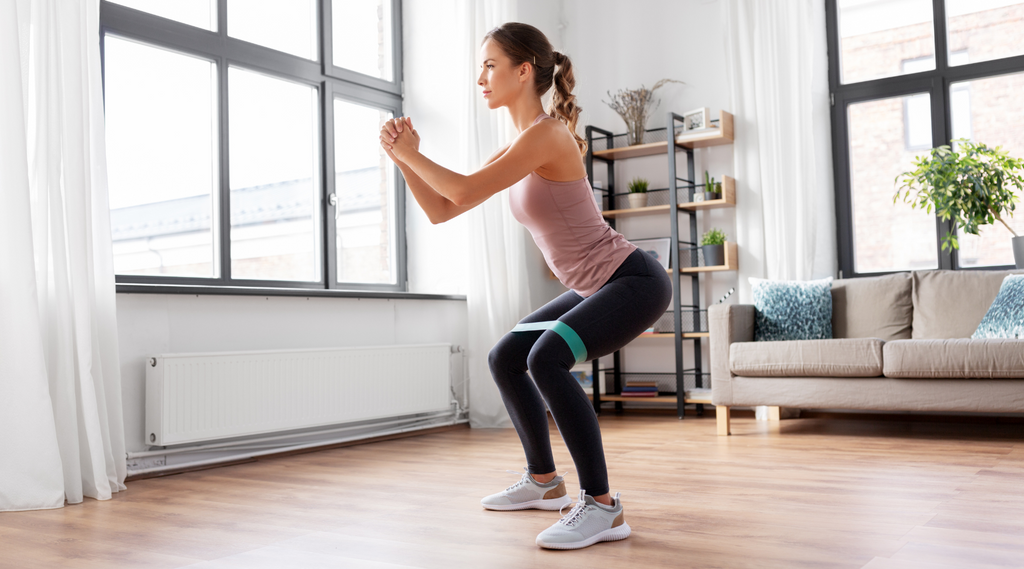 A woman performing front squats, an exercise usually integrated in  home workouts with resistance bands.