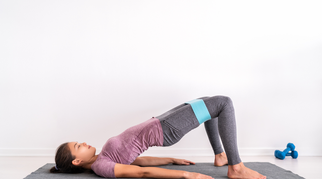 A woman gracefully performing glute bridges with resistance bands.