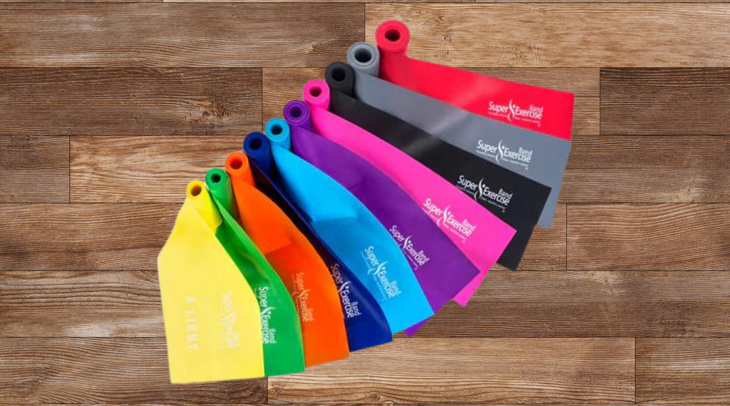 A collection of vibrant resistance bands arranged on a wooden floor, showcasing an array of colors.