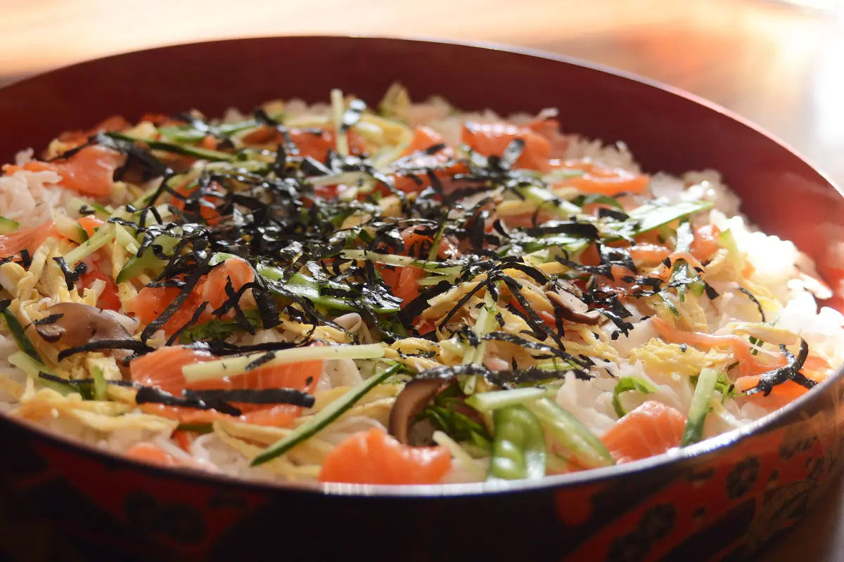 Chirashi Sushi is a dish made of sushi rice flavored with vinegar, sugar and salt, on top of which you can put any ingredients that you like. The common ingredients are sashimi raw fish, kinshi tamago (shredded egg crepe), shrimps, lotus roots, beans, sliced green shiso leafs or sliced seaweed.