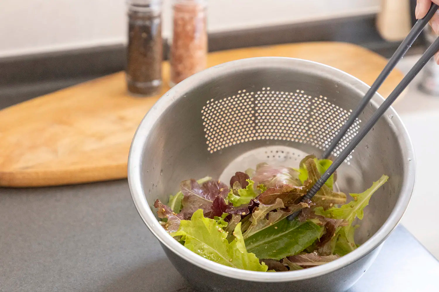 Mixing lettuce with dressing in the bowl