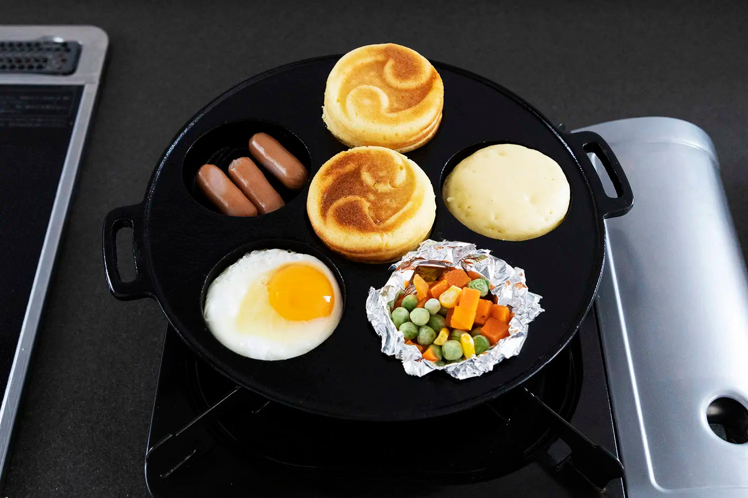 Weiners, vegetables, and eggs cooking together with obanyaki in the Gifu-Asahi Obanyaki Pan