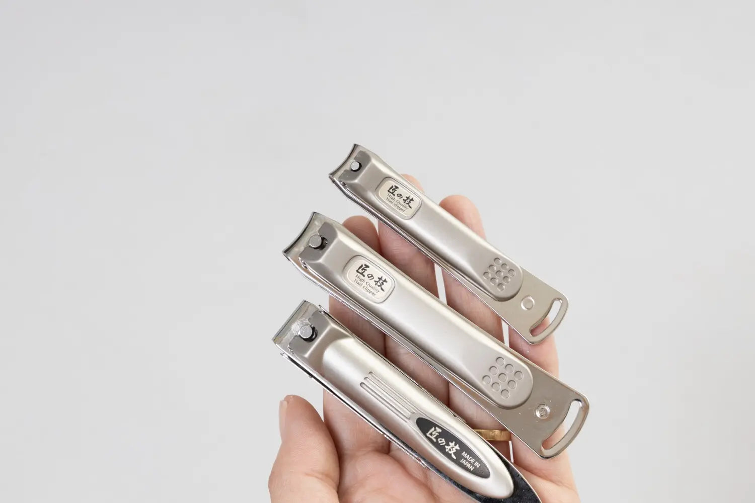 Three nail clippers being held