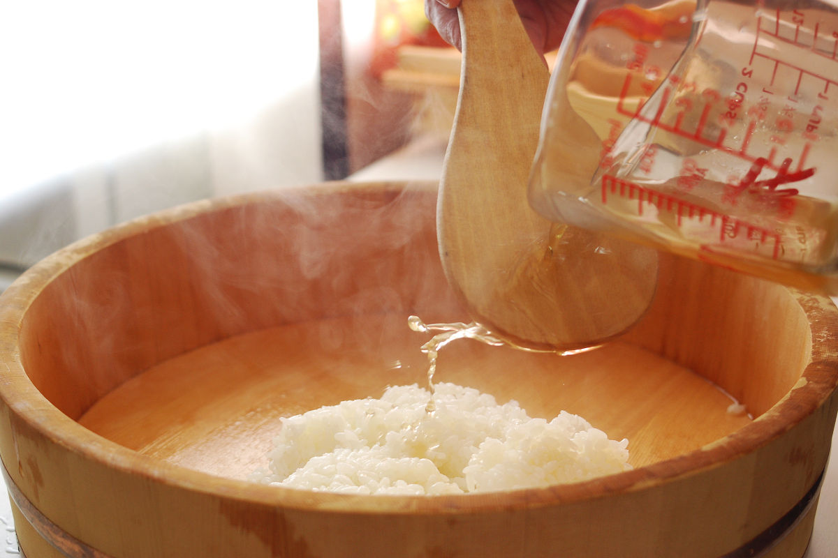 Mix cooked rice and vinegar in a wooden rice container. 