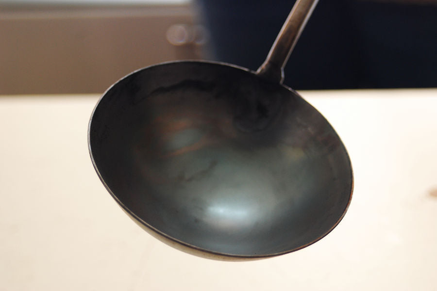 Once the wok turns gray with varnish burned off, let it cool.