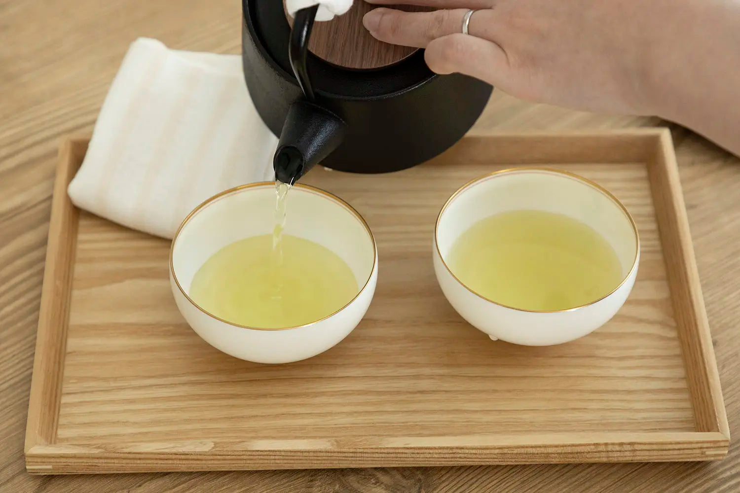 Pouring hot tea into teacup to serve