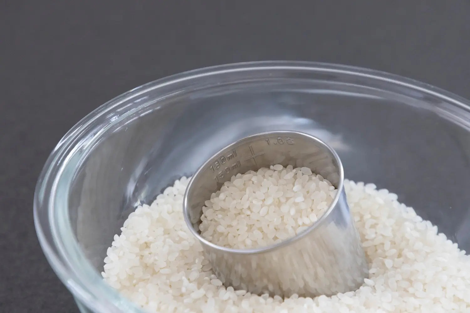 Rice in glass bowl with measuring cup