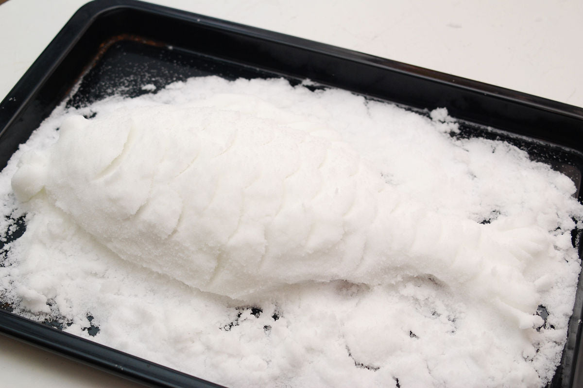 Put salt on a baking tray of oven and lay the sea bream, then make a salt crust on it.