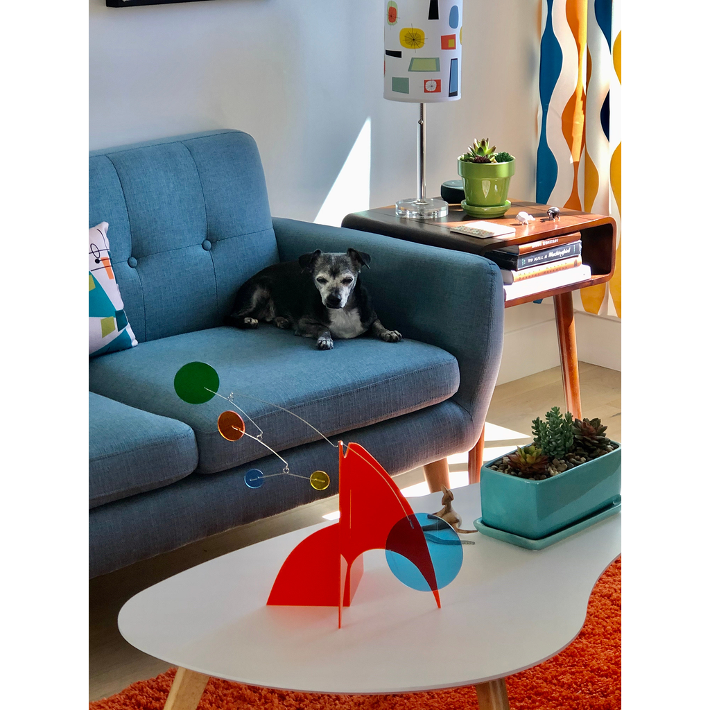 Lindo perrito mirando la escultura estable Moderne en naranja y varios colores sobre una moderna mesa de café en una moderna sala de estar de mediados de siglo de AtomicMobiles.com