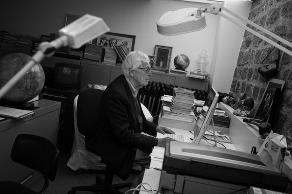 John Morris at his desk with photo of Robert Capa on his desk.