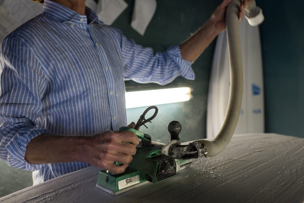 close up of a man sanding a custom surf board in cape hatteras, North Carolina