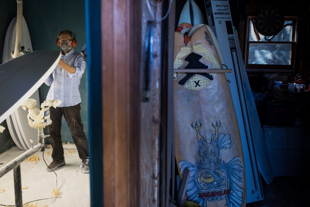 Man working in a surf shop to create a custom surf board