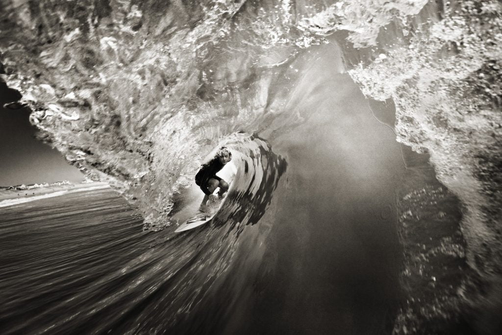 Black and white photo of a surfer in the middle of a wave 