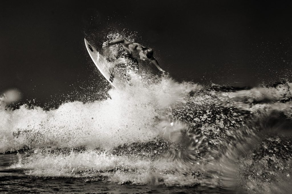 Black and white image of a surfer at the crest of a wave