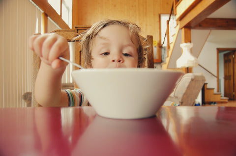A kid eating a bowl of noodles.