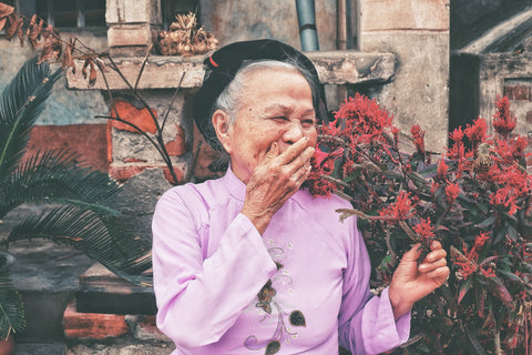 An elderly happy women in a pink dress.