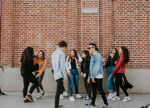 A large group of happy people with a red brick wall.