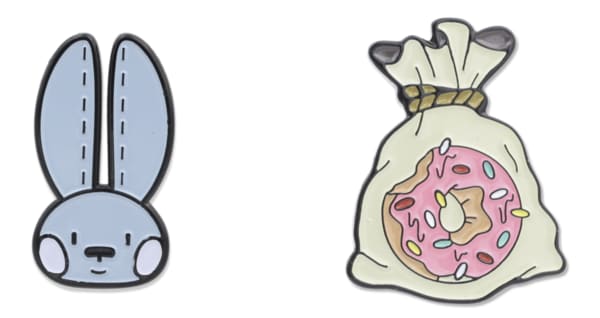 Two enamel pins, one shaped like a rabbit the other a donut in a bag