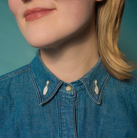 woman wearing two enamel pins shaped like bowling ball pins