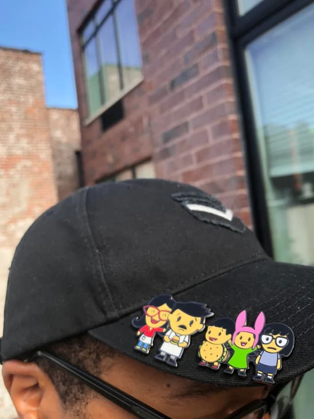 Cap with several enamel pins on the brim