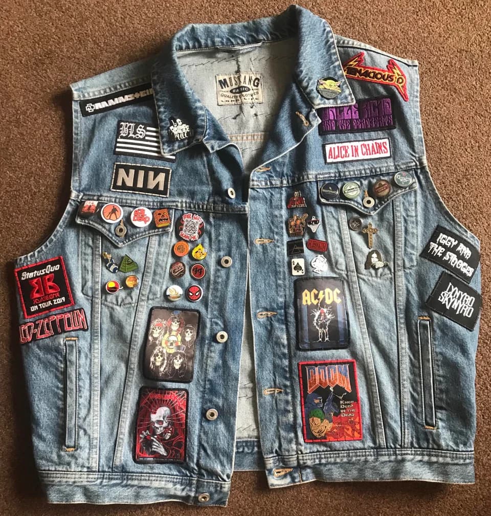 Denim vest filled with patches and enamel pins