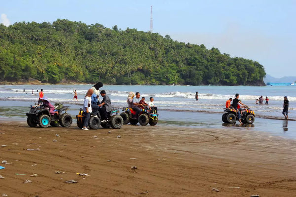 beberapa orang bermain ATV di tepi pantai air manis
