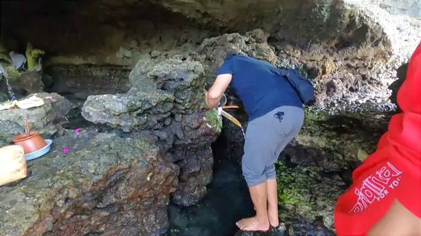 pengunjung mengambil air di gua air suci