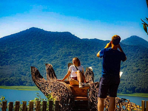 seorang lelaki sedang memfoto seorang wanita di spot foto tangan raksasa wanagiri hidden hills