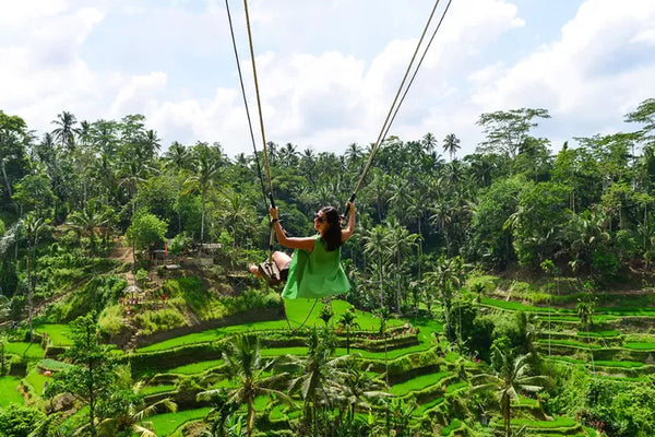 seorang wanita bermain ayunan besar dengan latar belakang terasering tegalalang