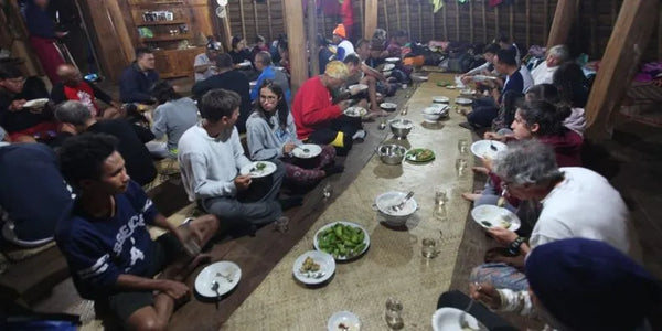 para pengunjung desa wae rebo sedang menikmati makan di dalam rumah adatnya