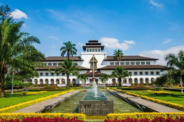 pemandangan salah satu gedung ikonik di bandung yang dikelilingi dengan bunga berwarna merah, kuning, dan hijau