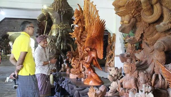 seorang wisatawan sedang melihat hasil karya patung-patung dari pengrajin lokal di desa pakraman pakudui