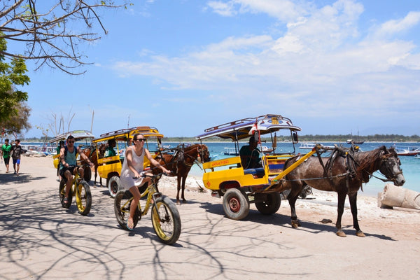 orang orang sedang bersepeda dan berkuda di tepi pantai gili trawangan