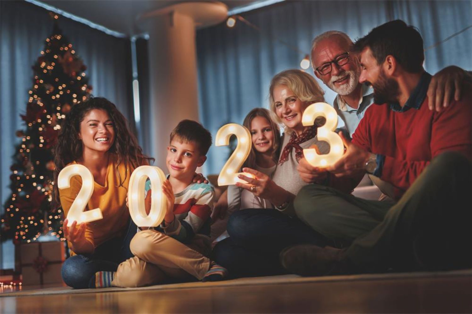 family taking photo by holding '2023' lighting signs with Christmas tree
