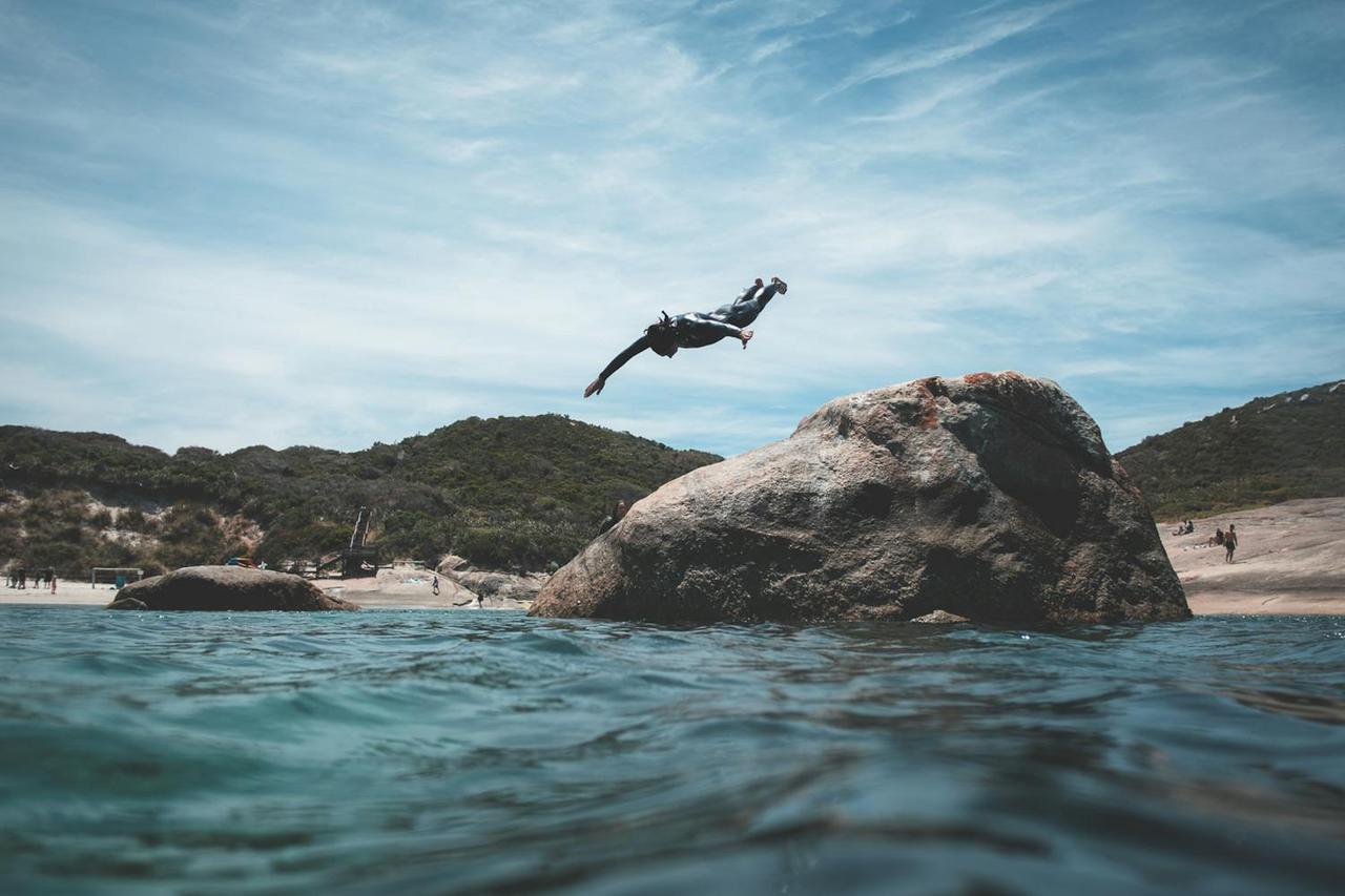 A person diving into the ocean from a large rock