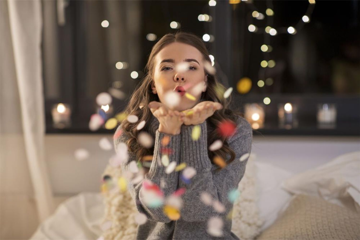 girl blowing confetti on bed