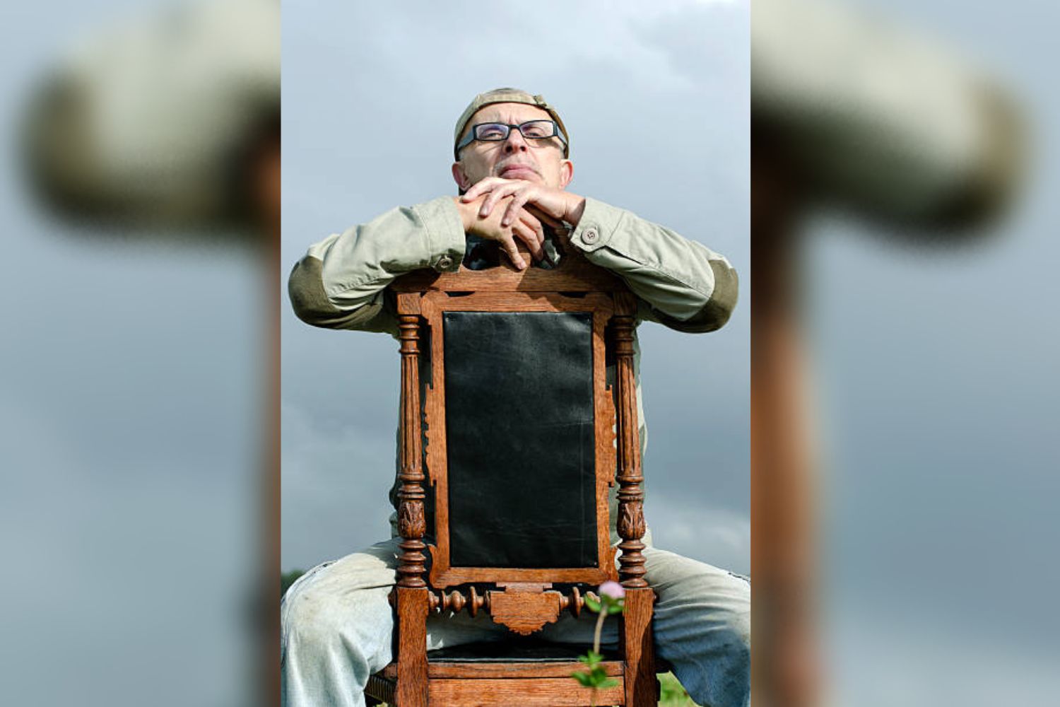 a man is taking photo by sitting on a backward chair