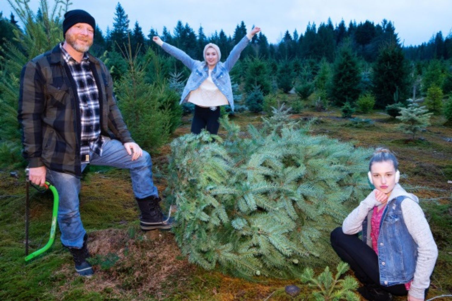 family taking picutre with the Christmas tree cut down