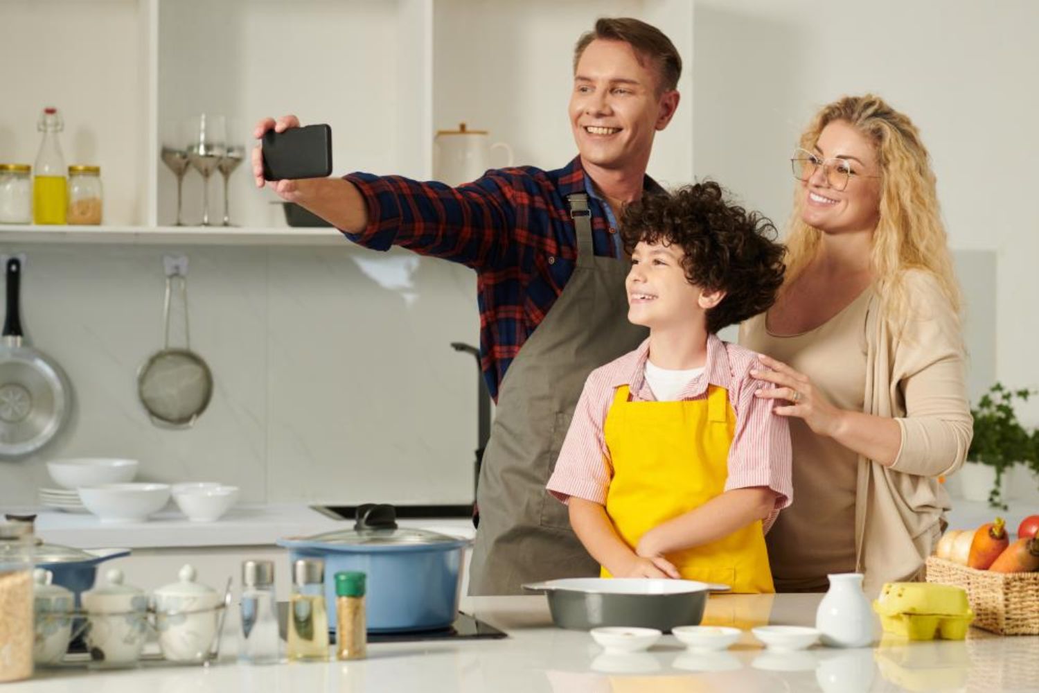 parents and thier boy taking photo of preparing food in the kitchen