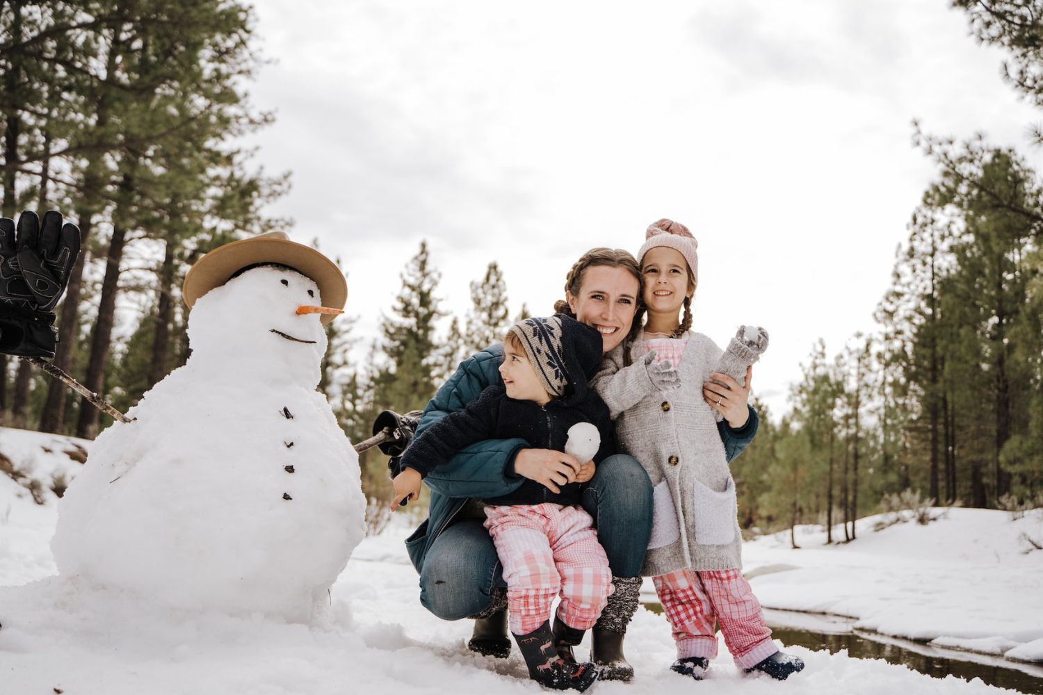 mum and kids standing beside a little snowman