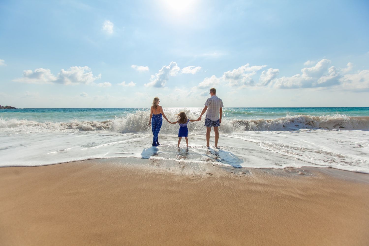 mom, dad and daughter  standing in the beach water