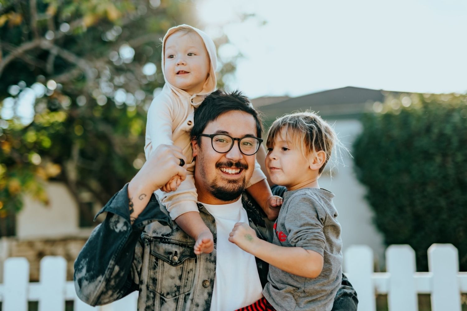 photo of father holding kids on his back