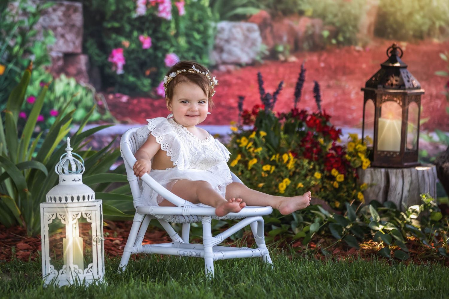 a baby sitting on chair in front of a flower garden